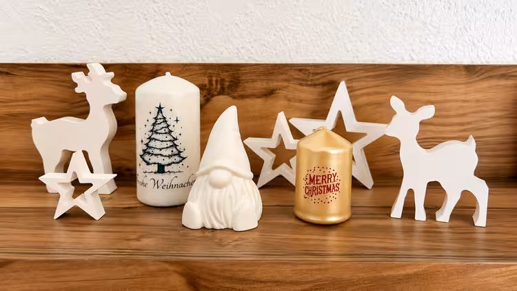 Weihnachtliche Dekoration mit bedruckten Kerzen, Sternen, Wichtel und Rentieren auf einem Holzregal